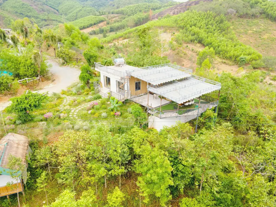 Nhà trắng mái bằng và deck cỏ đua ra sườn đồi